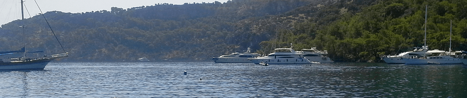 Yachten in ruhiger Bucht vor bewaldeten Hügeln an der Adria