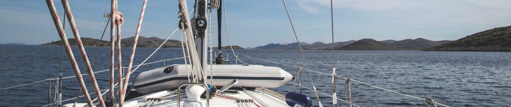 Blick über das Vorschiff einer Segelyacht auf eine kroatische Inselkette
